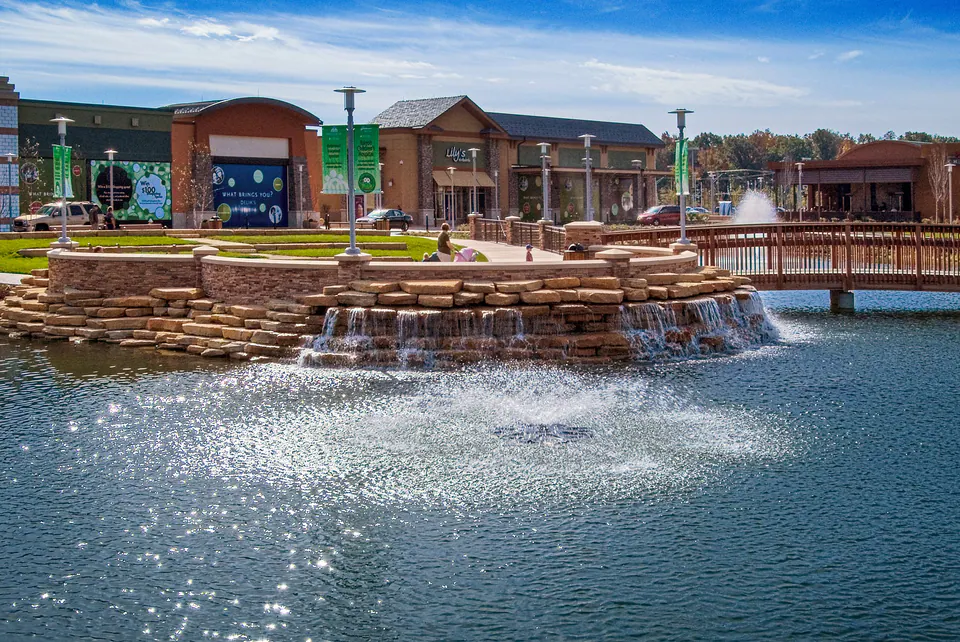 Commercial pond with natural stone waterfall, bridge railing, and fountain spray